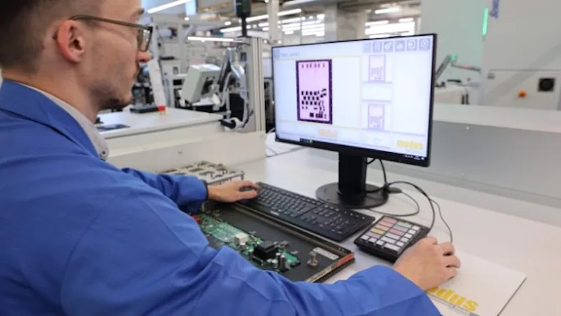 Operario de la fábrica capturando imágenes de una PCB de producción y marcando zonas con posibles defectos antes de pasarla a la programación manual de la AOI