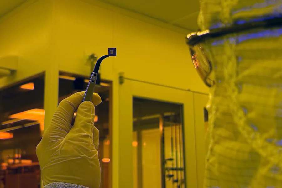 Un investigador sostiene un pequeño chip que contiene cientos de dispositivos